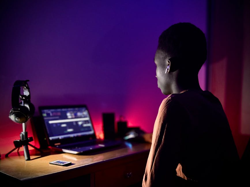 A teenager using a laptop with purple ambient lighting, symbolizing technology and modern living